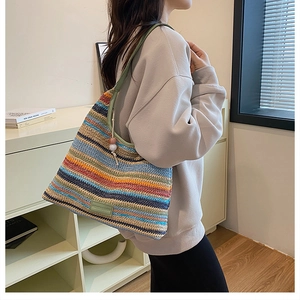 Detail of colorful rainbow striped woven tote bag with green leather shoulder strap