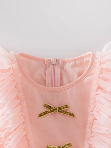Detail showing the pink neckline with mesh ruffles and a golden glitter bow decoration