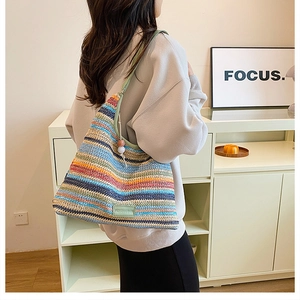 Detail of colorful striped woven hobo bag with beaded strap and textured cotton fabric