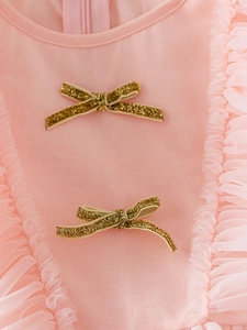 Detail of pink cotton dress with golden glitter bows and soft tulle ruffle neckline