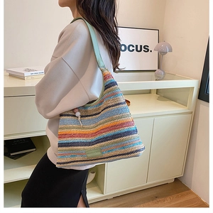 Detailed view of a multi-colored striped woven shoulder bag with a green leather strap