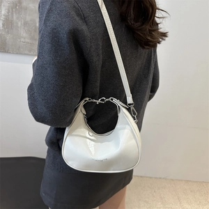 White glossy leather crescent bag with adjustable strap shown on a model side view