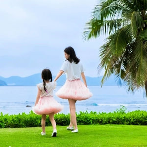 Outdoor view of mother and daughter matching pink tutu skirts by the sea