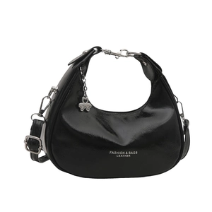 Chic black crescent hobo bag in glossy leather with adjustable strap and clover pendant