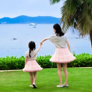 Pink layered tutu skirts for mother and daughter on a sunny coastal meadow landscape