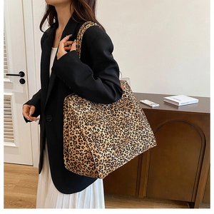 Detailed side view of large leopard print canvas tote bag carried by a model