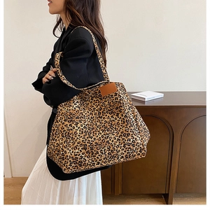 Side view of large leopard print tote bag with brown leather tag on model