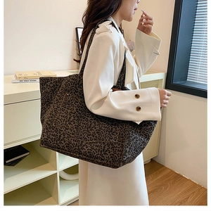 Detailed view of leopard print canvas tote bag with side pocket shown on a shoulder