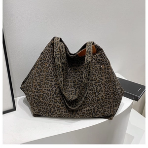 Detail view of leopard print canvas tote bag with metal rivets and leather tag on display