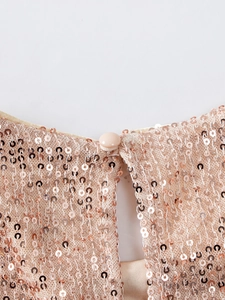 Macro detail of champagne sequins fabric with a button closure and keyhole back design