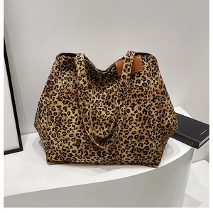 Detail of leopard print canvas tote bag featuring premium leather handles and dual outer pockets