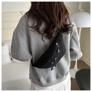 Detailed close-up of black corduroy chest bag featuring unique triangular zipper pulls