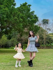 Outdoor shot of a woman in a blue mesh skirt and a girl in an off-white puffy tutu dress