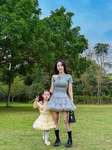 Outdoor shot of mother in grey tiered tutu skirt and daughter in yellow ruffle dress
