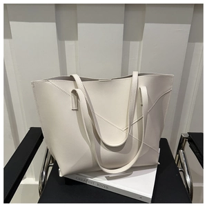 Dettaglio di una borsa tote bianca minimalista con cuciture a V su una sedia in pelle