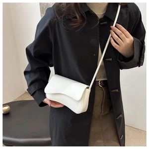 Chic white crossbody bag with wave-edge flap and thin leather strap on a model