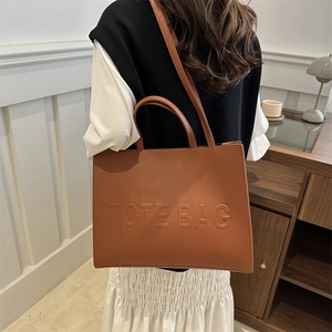 Brown leather tote bag with embossed text and dual straps for shoulder or hand carry