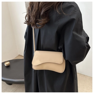 Detail of a chic cream shoulder bag with wave edge flap and smooth leather texture