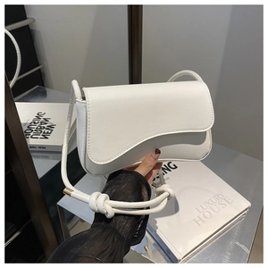 Detail of white leather shoulder bag with unique wavy flap and golden metallic hardware