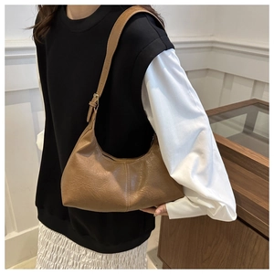 Brown vintage faux leather hobo bag styled on shoulder with minimalist adjustable strap