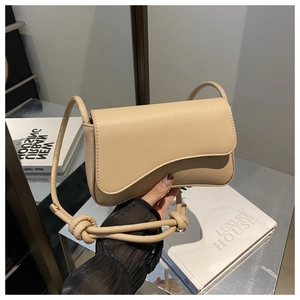 Detail of beige faux leather shoulder bag with unique knotted strap and asymmetric flap