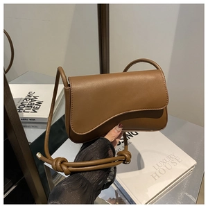 Detailed macro view of caramel brown PU leather bag with decorative large knot on strap