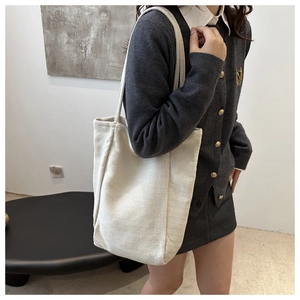 Détail du sac cabas en toile crème avec tissage à chevrons porté par un mannequin