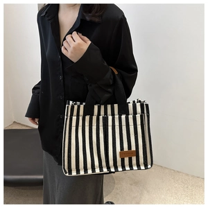 Detail of black and white striped canvas tote with brown leather fashion label