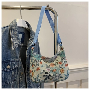 Detailed texture of floral jacquard fabric and adjustable blue strap on a crossbody bag