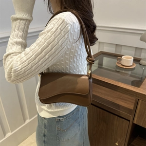 Minimalist dark brown leather underarm bag with unique wave flap and thin shoulder strap