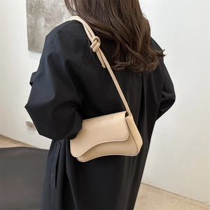 Beige shoulder bag with irregular flap and knotted strap shown on model side view
