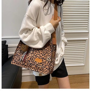 Detail of leopard print tote bag with brown shoulder strap and cute plush bear charm
