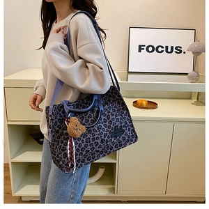 Detail of purple leopard canvas tote bag featuring plush bear charm and focus label