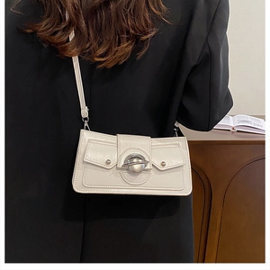 Mannequin portant un sac bandoulière en cuir blanc avec boucle argentée sur un blazer noir