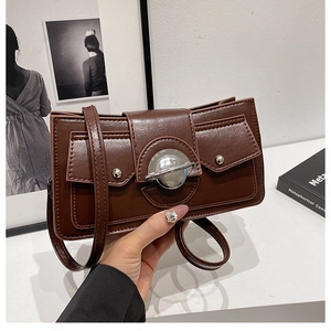 Gros plan d'un sac porté épaule vintage marron foncé avec une grande boucle en métal argenté