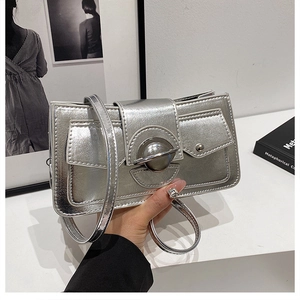 Détail du sac bandoulière argenté métallisé avec boucle ronde et rabat avant minimaliste