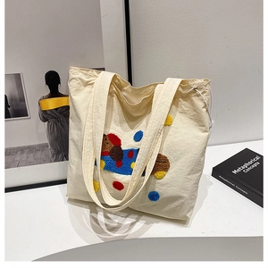 Gros plan sur la broderie colorée et le tissu texturé d'un grand sac fourre-tout