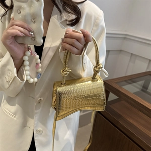 Metallic gold hourglass handbag with crocodile texture and knot handle on model