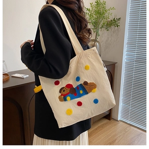 Détail de la broderie de chien et des pois colorés sur le sac cabas en toile écrue