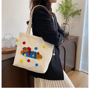 Détail du patch brodé de chien mignon sur un sac fourre-tout en toile blanc cassé porté