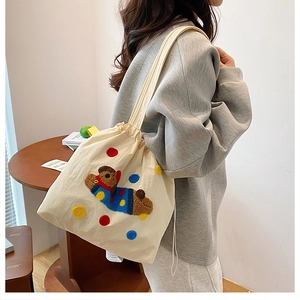 Détail du sac cabas en toile blanc cassé avec broderie colorée et fermeture par cordon