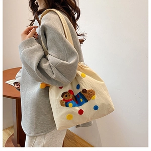 Détail du motif d'ours brodé sur le sac cabas en toile beige à cordon de serrage