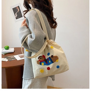 Détail de la broderie ours mignonne et du cordon sur un sac cabas en toile beige