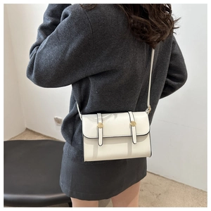 Sac bandoulière carré en cuir blanc minimaliste avec détails métalliques dorés circulaires