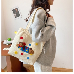 Détail de la broderie chien mignon sur un sac fourre-tout en toile beige à pois colorés