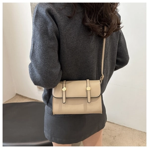 Détail du sac bandoulière beige en similicuir avec boucles dorées et sangles verticales