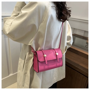 Vue détaillée du sac à bandoulière rose avec boucle dorée porté par un modèle