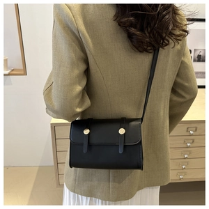 Mannequin portant un sac bandoulière carré noir minimaliste avec boucles dorées en studio