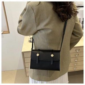 Vue mannequin montrant le profil arrière d'un sac bandoulière noir aux détails dorés