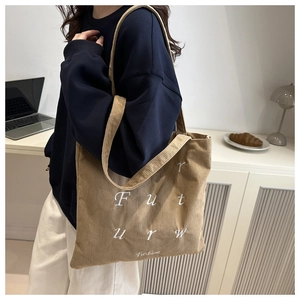 Detail of khaki corduroy tote bag with Futurw embroidery in an office setting